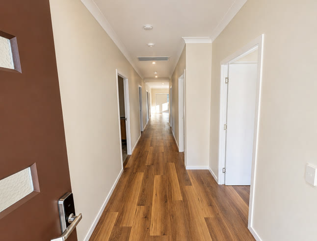 Wide hallway running the length of the house from the front door, level throughout, with doorways opening off both sides.